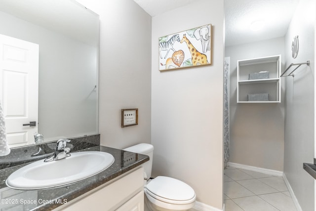 bathroom featuring toilet, vanity, baseboards, and tile patterned floors