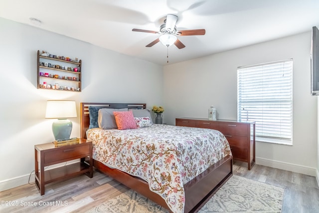 bedroom with ceiling fan, light wood finished floors, and baseboards