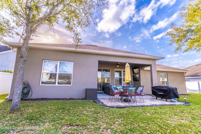 rear view of property with a yard, a ceiling fan, a patio, and stucco siding