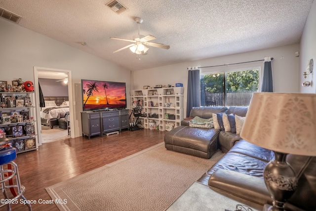 living room with ceiling fan, visible vents, vaulted ceiling, and wood finished floors