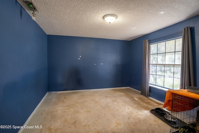 carpeted empty room featuring a textured ceiling and baseboards