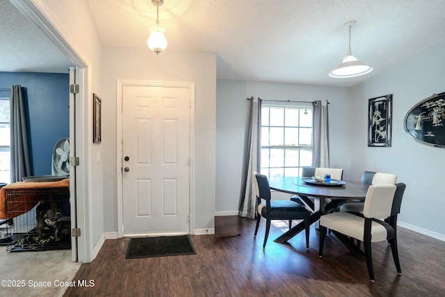 dining area with a textured ceiling, dark wood-style flooring, and baseboards