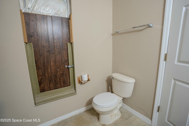 bathroom featuring tile patterned flooring, toilet, and baseboards