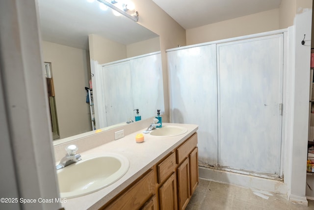 full bath featuring double vanity, a stall shower, a sink, and tile patterned floors