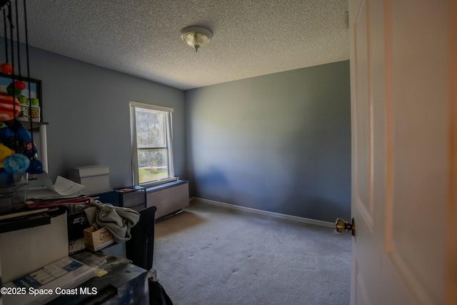 carpeted office with baseboards and a textured ceiling