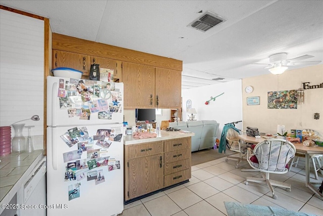 kitchen with white appliances, a ceiling fan, visible vents, light tile patterned flooring, and light countertops