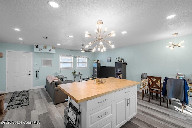 kitchen featuring light wood-type flooring, a notable chandelier, butcher block counters, and white cabinetry