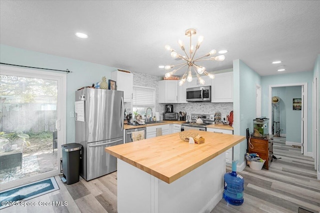 kitchen featuring a sink, a notable chandelier, appliances with stainless steel finishes, and white cabinetry