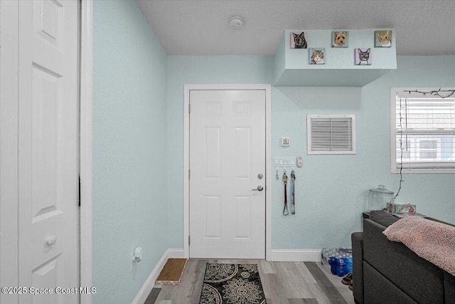 foyer with visible vents, baseboards, and wood finished floors