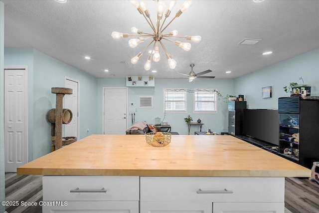 kitchen featuring a textured ceiling, white cabinets, butcher block counters, and ceiling fan with notable chandelier