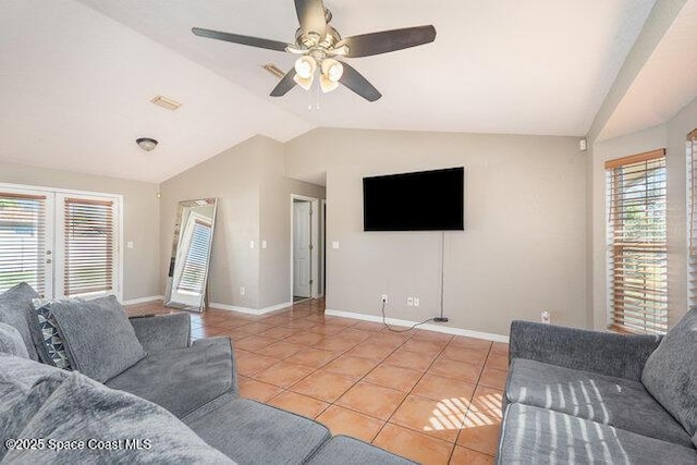 tiled living area featuring lofted ceiling, a healthy amount of sunlight, baseboards, and a ceiling fan