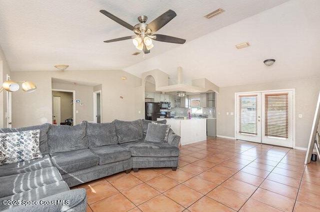 living area featuring light tile patterned floors, visible vents, baseboards, ceiling fan, and vaulted ceiling