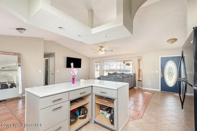 kitchen with light tile patterned floors, lofted ceiling, light countertops, freestanding refrigerator, and open shelves