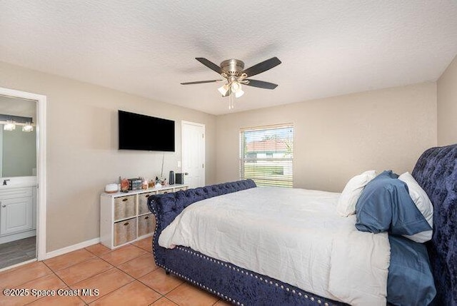 bedroom with light tile patterned flooring, ceiling fan, a textured ceiling, ensuite bath, and baseboards