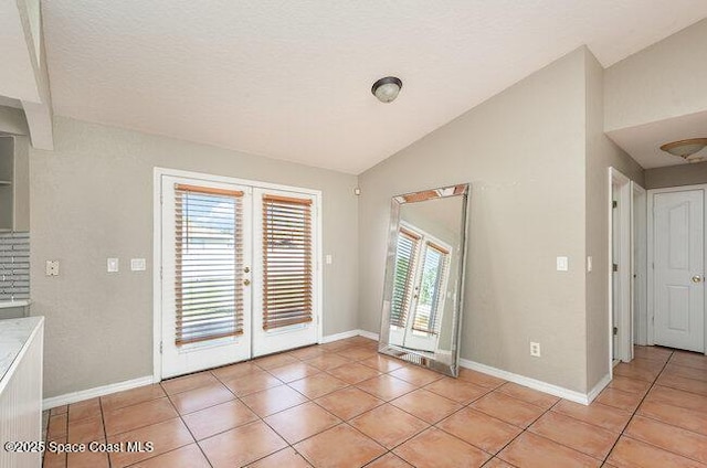 interior space featuring french doors, light tile patterned flooring, vaulted ceiling, and baseboards