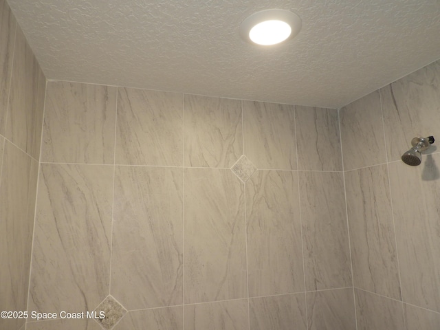 room details featuring tiled shower and a textured ceiling