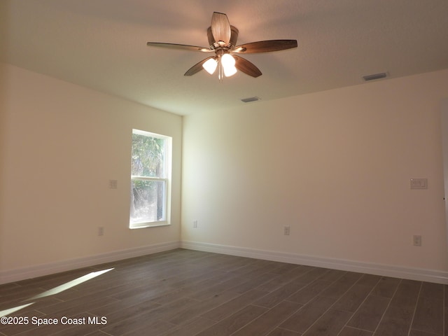 spare room featuring dark wood-style flooring, visible vents, and baseboards