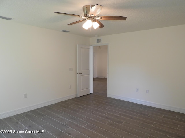 empty room with baseboards, visible vents, and dark wood finished floors