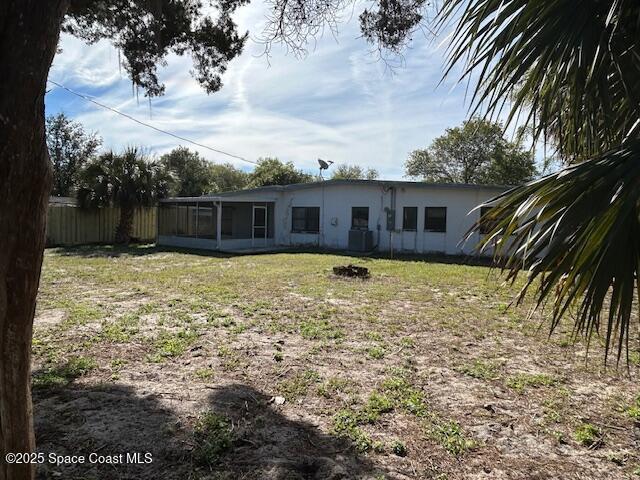 back of property with a yard, a sunroom, and fence