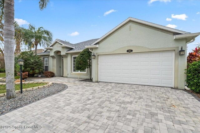 ranch-style home with stucco siding, driveway, and an attached garage