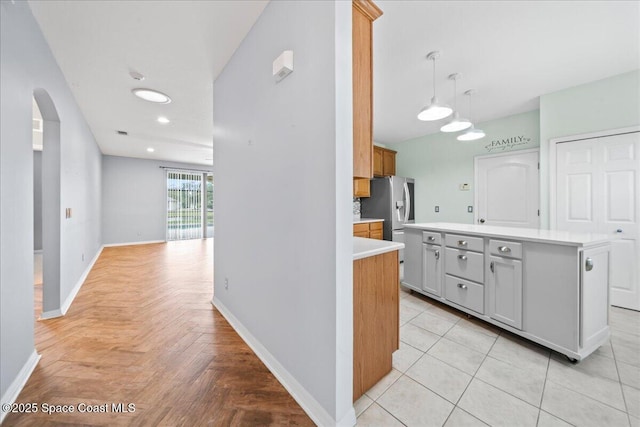 kitchen featuring light countertops, baseboards, arched walkways, and a kitchen island