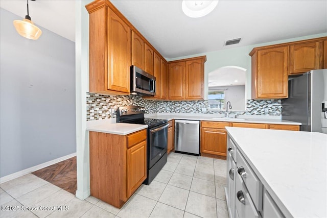 kitchen with visible vents, arched walkways, a sink, light countertops, and appliances with stainless steel finishes