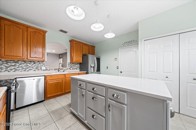 kitchen with appliances with stainless steel finishes, a kitchen island, and light countertops