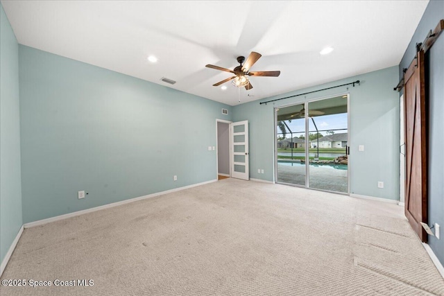 unfurnished room with baseboards, visible vents, recessed lighting, ceiling fan, and a barn door