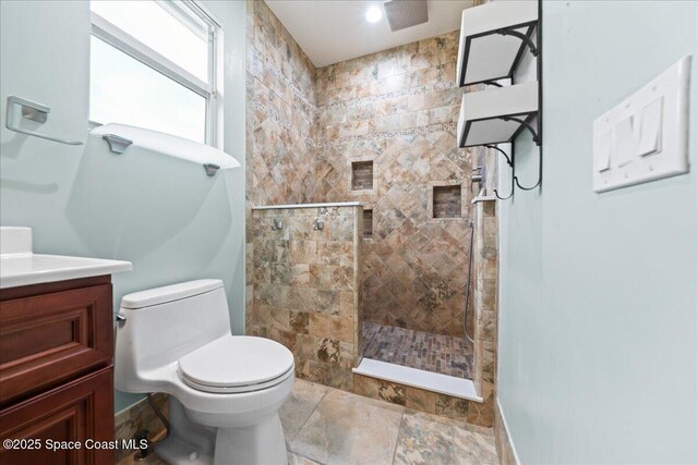 full bath with vanity, toilet, a walk in shower, and stone finish flooring