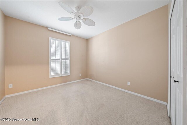 carpeted spare room with baseboards and ceiling fan