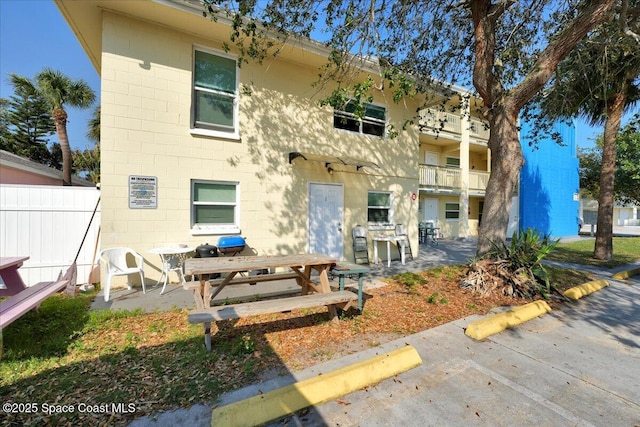 rear view of property with fence, concrete block siding, and a patio area