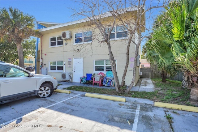 view of front of property with concrete block siding, fence, and uncovered parking