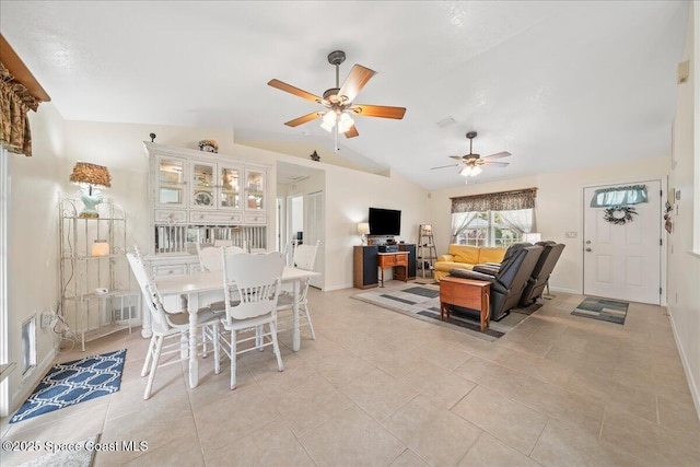 living area featuring lofted ceiling, light tile patterned floors, visible vents, baseboards, and a ceiling fan