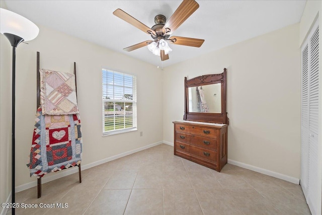 living area with a ceiling fan, light tile patterned flooring, and baseboards