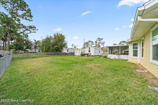 view of yard featuring an outbuilding, a sunroom, a fenced backyard, and a storage unit