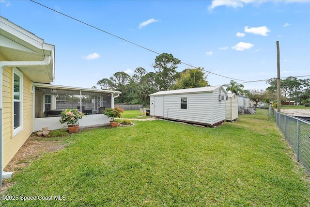 view of yard with a sunroom, a fenced backyard, a storage shed, and an outbuilding