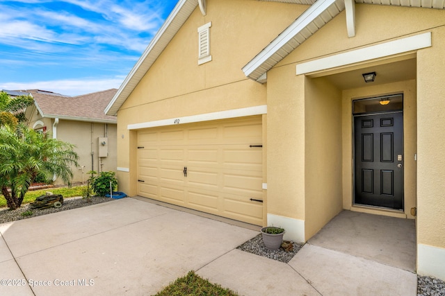 exterior space with a garage, concrete driveway, and stucco siding