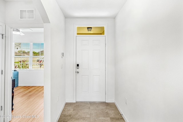 foyer with arched walkways, visible vents, and baseboards