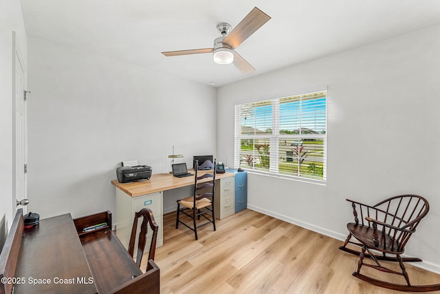 office area with light wood-type flooring, ceiling fan, and baseboards