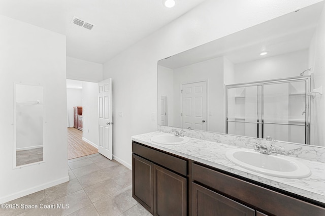 full bathroom with a sink, visible vents, baseboards, a shower stall, and double vanity