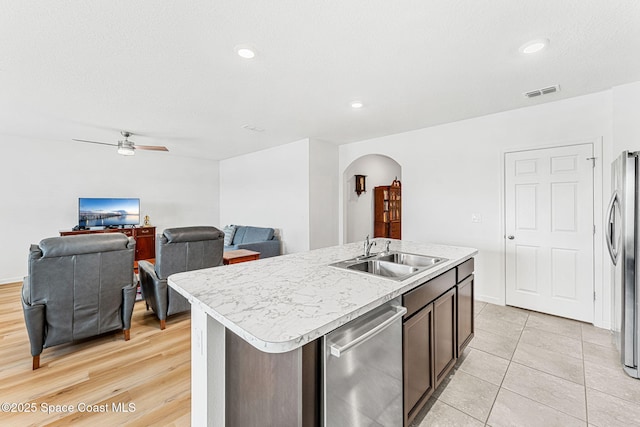 kitchen featuring arched walkways, stainless steel appliances, light countertops, visible vents, and a sink