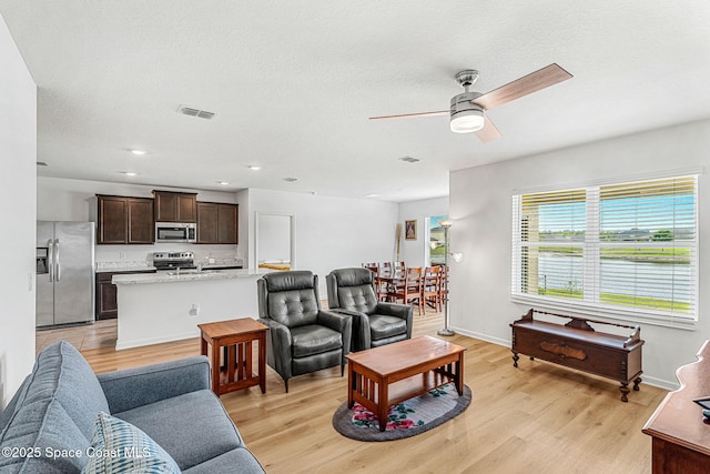 living area with ceiling fan, recessed lighting, visible vents, baseboards, and light wood-style floors