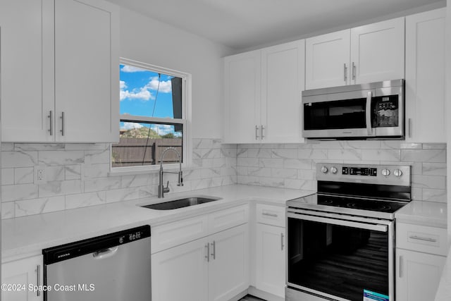 kitchen with decorative backsplash, appliances with stainless steel finishes, light countertops, white cabinetry, and a sink