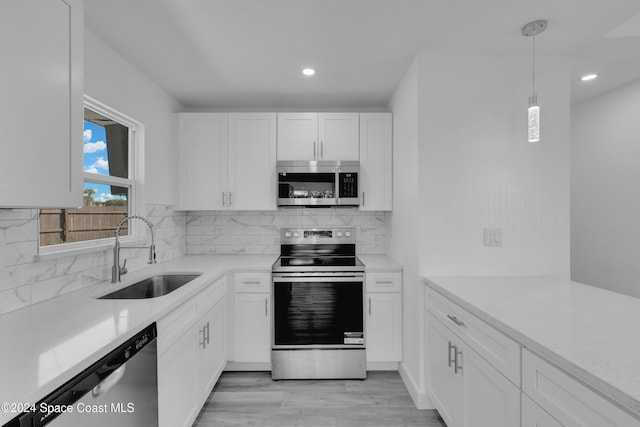 kitchen with stainless steel appliances, a sink, white cabinetry, and decorative backsplash