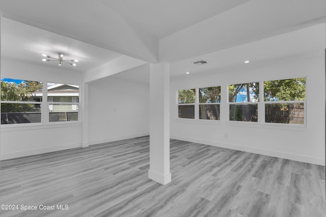 empty room featuring a wealth of natural light, baseboards, and wood finished floors