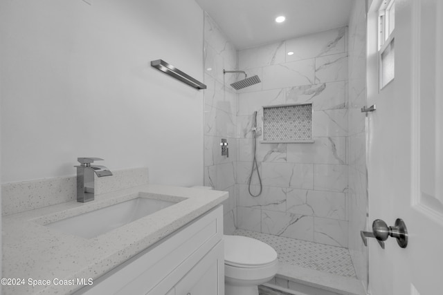 full bath featuring toilet, vanity, and a marble finish shower