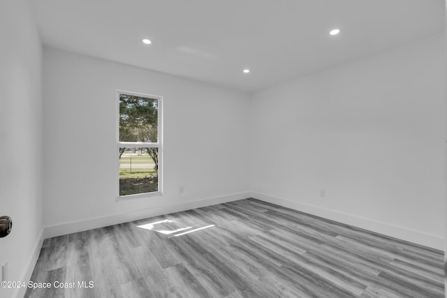 spare room featuring recessed lighting, baseboards, and wood finished floors