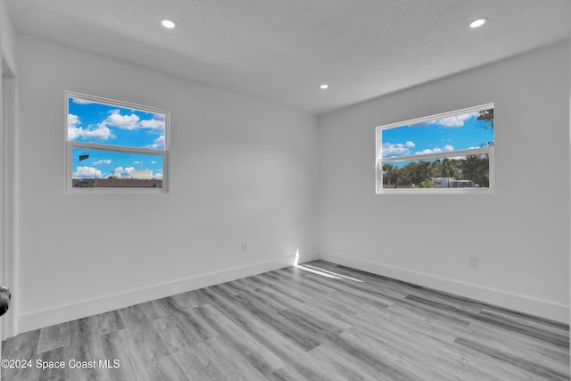 unfurnished room with baseboards, wood finished floors, and recessed lighting