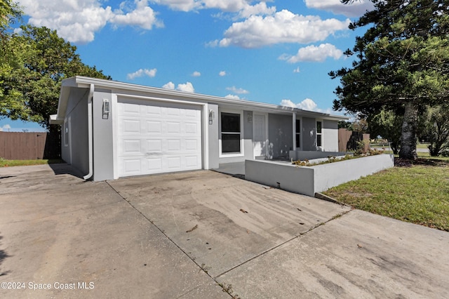 ranch-style home with a garage, concrete driveway, fence, and stucco siding