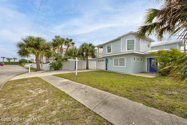 view of front of home featuring driveway, an attached garage, fence, a front lawn, and stucco siding